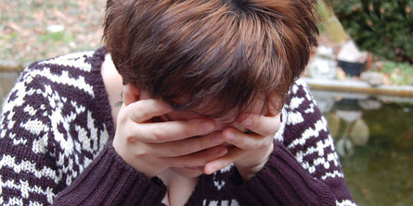 Imagem de mulher triste, com a cabeça abaixada e apoiada nas mãos (Foto: Free Images)