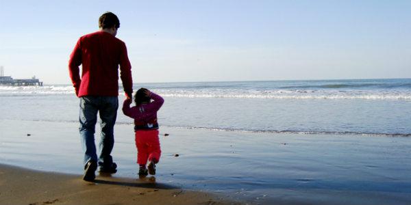 Imagem de pai segurando mãe de filha em caminhada na praia (Foto: Free Images)