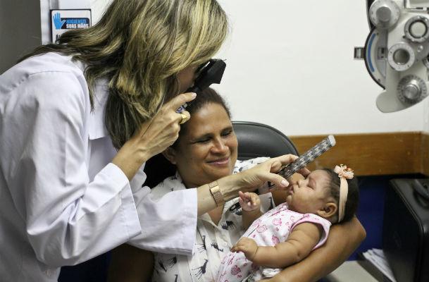 No colo da avó Ana Paula Silva, a menina Ágata, 3 meses, passa por exame oftalmológico (Foto: Sérgio Bernardo/JC Imagem)