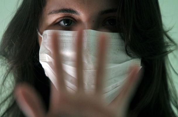 Imagem de mulher de máscara com mão espalmada em direção à câmera (Foto: Diego Nigro / JC Imagem)