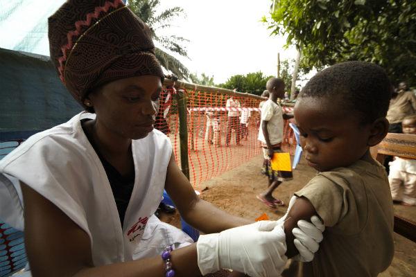 Imagem de voluntária aplicando vacina em menino (Foto: Roberto Riva / Divulgação)