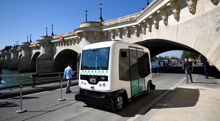 People watch a French capital's transport authority RATP electric-powered driverless EZ10 minibus, able to carry up to 12 passengers, carrying out its first test on the banks of the river Seine unde rthe Pont-Neuf bridge on September 24, 2016 in Paris.    The RATP carries out its first test of a driverless minibus, in the hope that regular routes for the hi-tech vehicles will be up and running within two years. One of the self-driving shuttle buses, made by French hi-tech firm Easymile,  run today along a special circuit in Paris on a pedestrianised street near the River Seine. / AFP / ERIC FEFERBERG