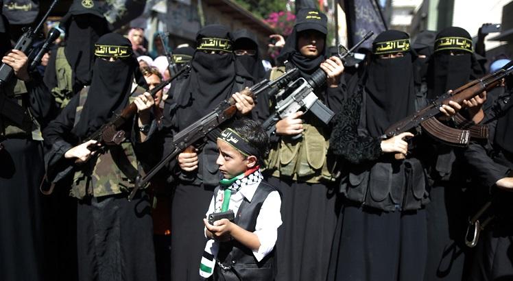 Garoto palestino segura uma arma em frente a passeata de mulheres do Movimento Islâmico de Jihad. AFP PHOTO / MAHMUD HAMS
