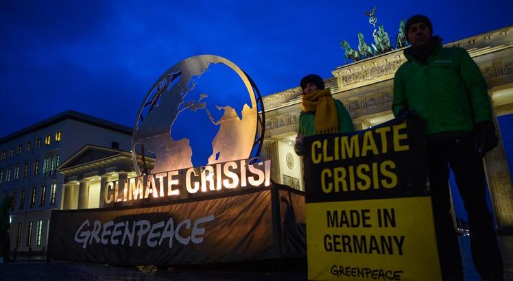 Os ambientalistas do Greenpeace fazem uma  demonstração ao lado de uma gigantesca instalação em forma de globo erguida em frente ao marco do Portão de Brandenburgo (Gregor Fischer / dpa / AFP) / Germany OUT