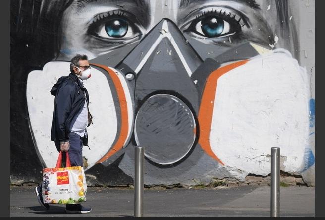 A máscara também é o tema desta pintura em muro de Milão, na Itália Foto: Daniele Mascolo / Reuters