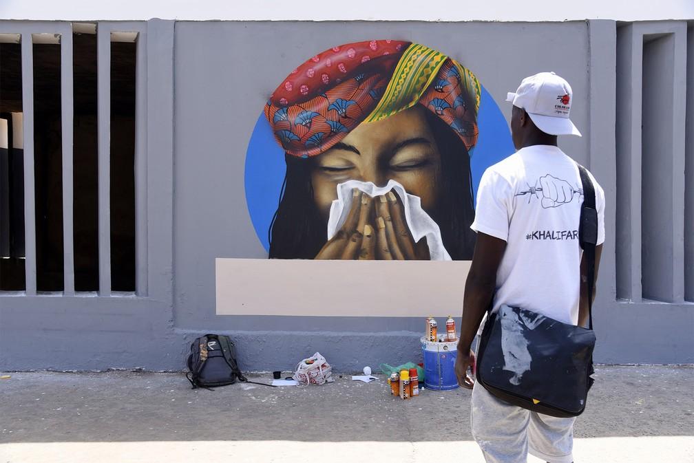 Artistas do grupo senegalês de grafite RBS Crew finalizam o desenho de uma mulher cobrindo o nariz com um lenço enquanto espirra, medida recomendada para prevenção contra o coronavírus, em um centro universitário de Dakar, no Senegal — Foto: Seyllou/Reuters
