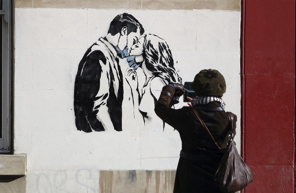 Mural surgido na Bank Street em Glasgow, na Escócia, que mostra um casal abaixando as máscaras para trocar um beijo. De autoria do artista de rua conhecido como Rebel Bear, a obra é inspirada em barreiras provocadas ela pandemia do coronavírus — Foto: Andrew Milligan/PA via AP